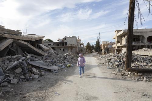 Palestinian refugee Malak Sabah walks between the rubble of buildings destroyed by Israeli bombardment in the city of Baalbek.